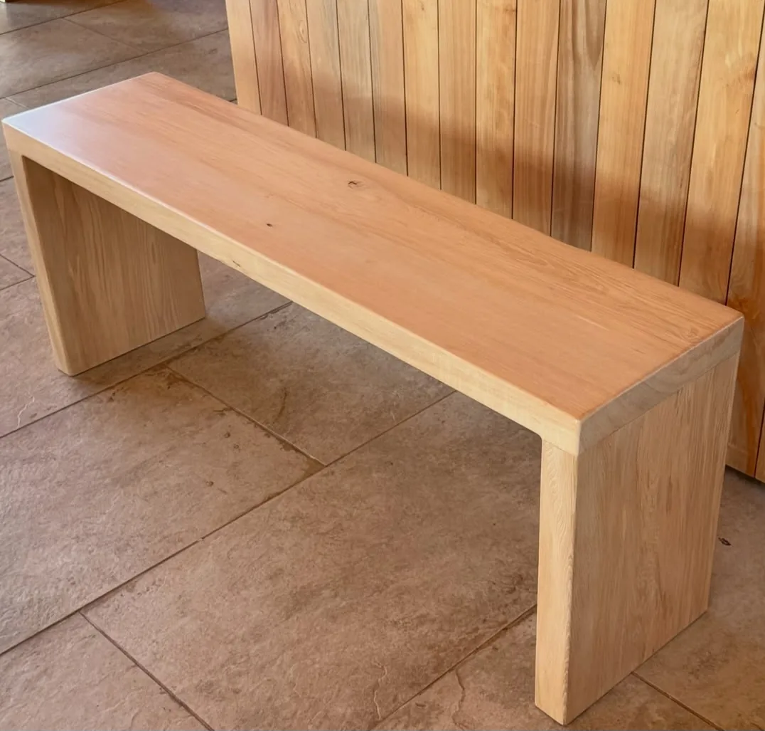Banca de madera clara de una sola pieza sobre piso de piedra