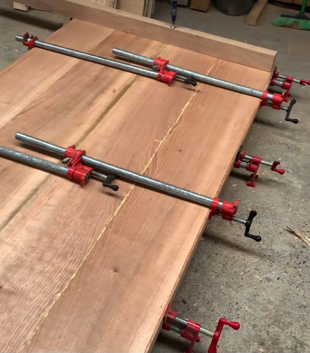 Tablones de madera prensados con tornos rojos durante el encolado
