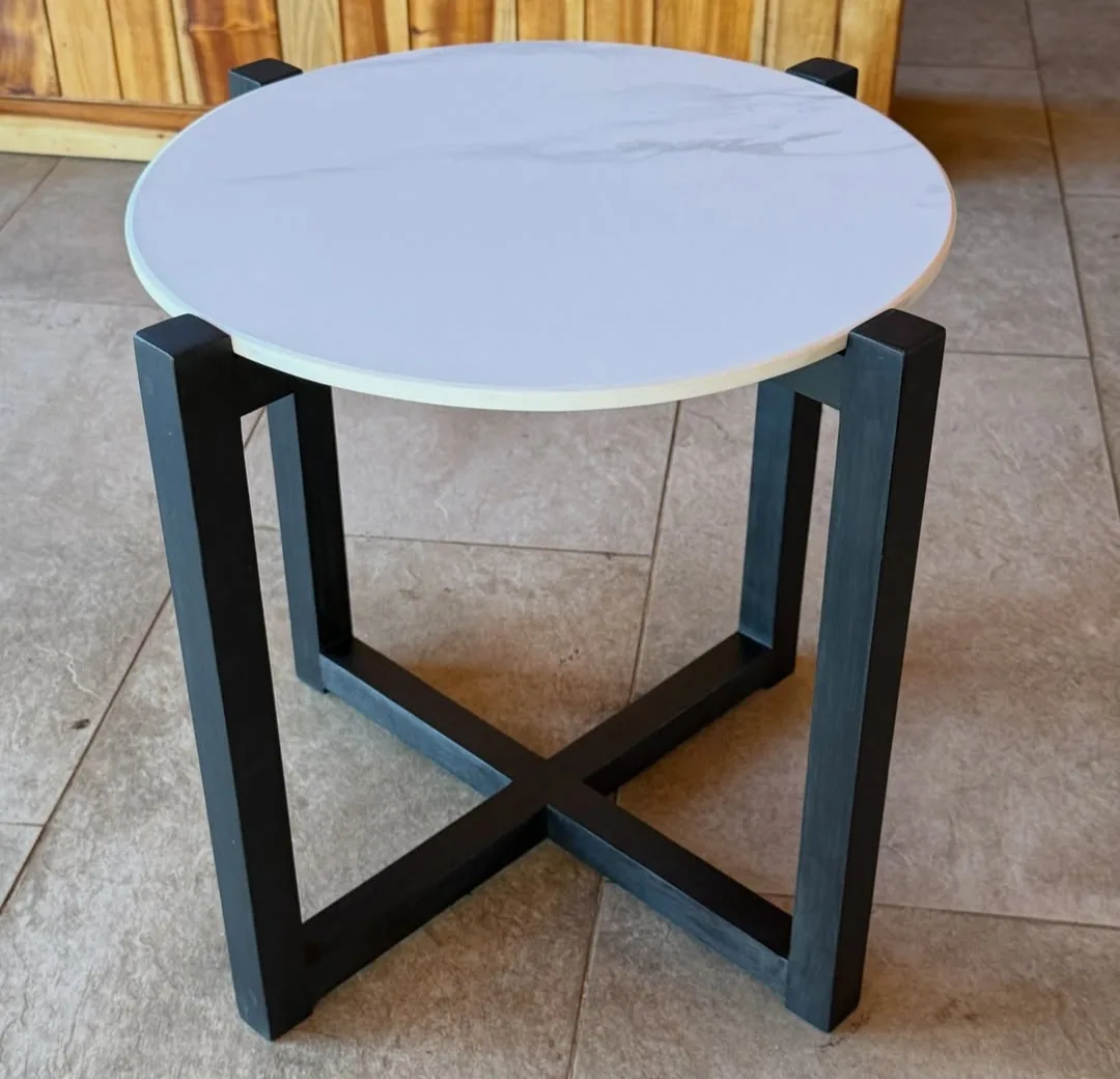 Mesa lateral redonda con cubierta blanca de porcelanato y estructura negra