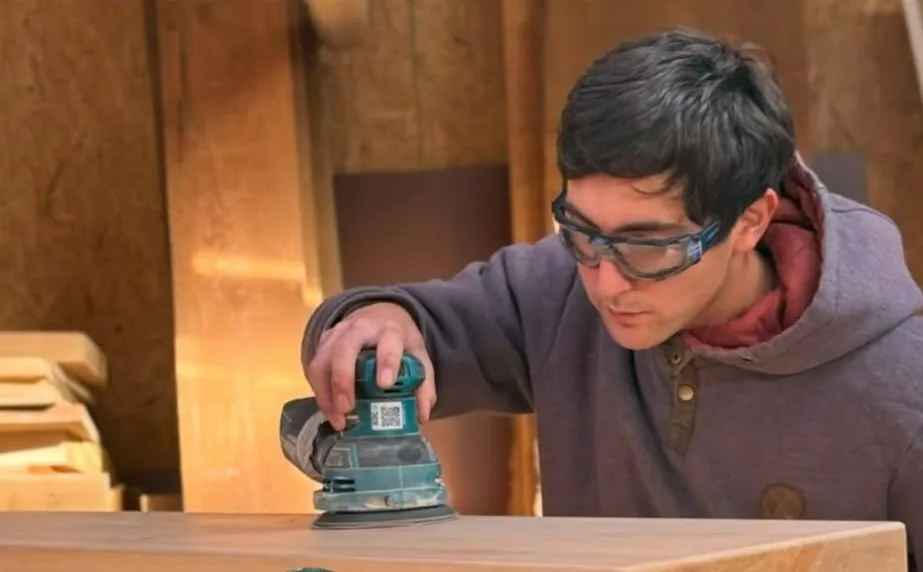 Ángel Zumelzo lijando una cubierta de madera en el taller